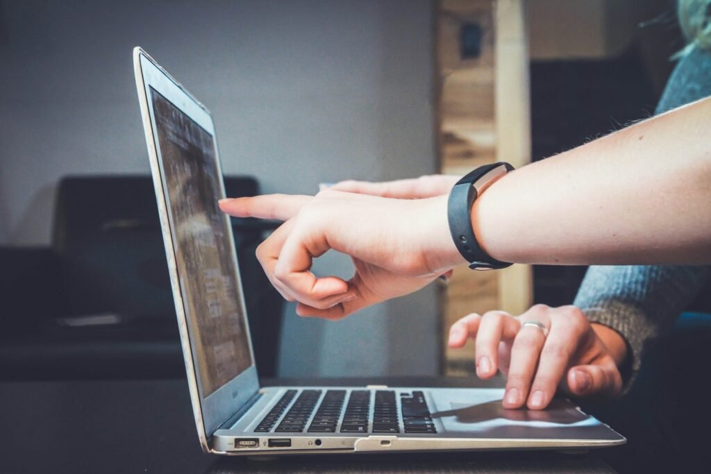 Two people pointing at a laptop screen during a discussion