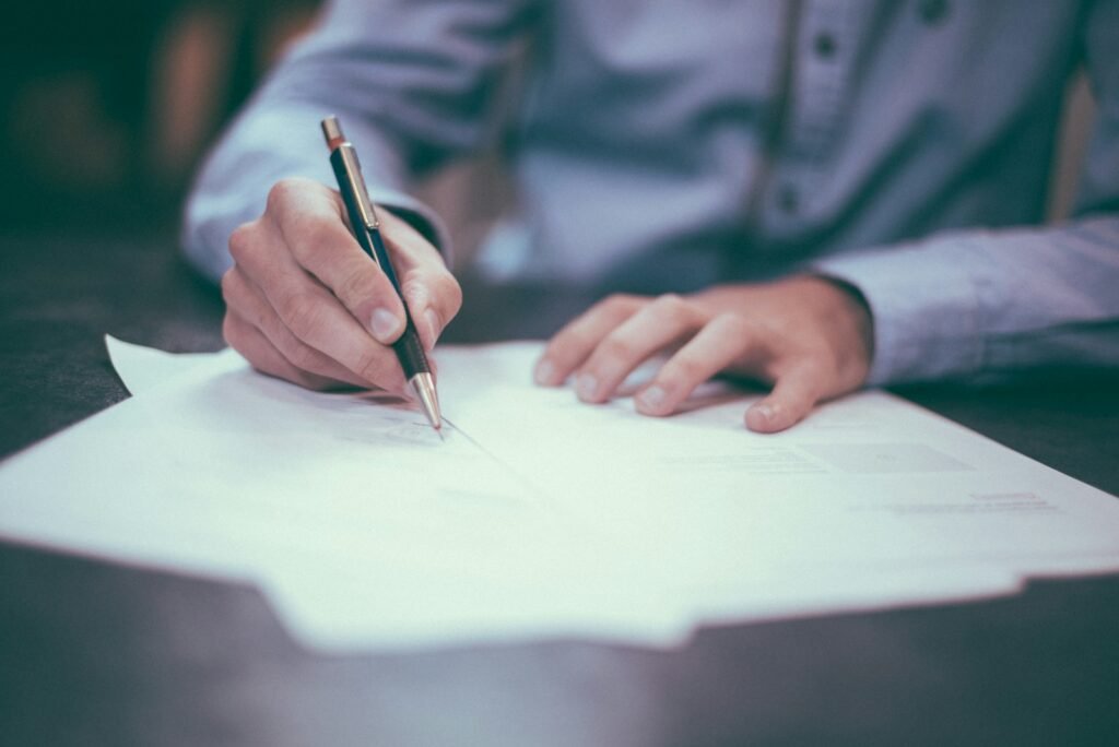 A person signing paperwork at a desk